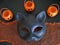 Top view closeup of fun Halloween cat mask and smiling mini jack-o-lanterns on black and orange backdrop.