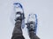 Top view closeup of a person wearing winter hiking snowshoes in snow