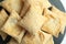 Top view closeup shot of a pile of square puff biscuits on a black pastry stand