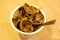 Top view closeup of walnuts shells in a plastic cup with a spoon on a wooden table