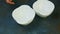 Top view closeup woman hands put two small empty white bowls on kitchen table