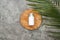 Top view of coconut beauty product in bottle on wooden board near palm leaf on grey textured background.