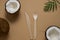 Top view coconuts, spoon and fork made of biodegradable materials on a light brown background