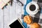 Top view of Coffee cup with bread, tablecloth, notebook, pen, glasses and Tablet on wooden table background.