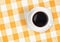 Top view of coffee cup on checked tablecloth