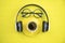 Top view of coffee cup with headphone and teacher glasses on yellow paper background