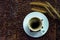 Top view of coffee cup on saucer with grass flowers and roasted coffee beans on wooden table