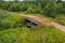 Top view of  the collapsing old bridge over an overgrown river