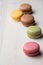 Top view of colored macarons, with selective focus, on white wooden table, vertica