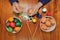 Top view of colorful Easter eggs are being painted with paintbrush and palette by young man on wooden table.