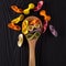 Top view of colorful farfalle pasta on black wooden table with spoon