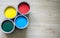 Top view of colorful four cans of paint ready for use on a wooden table