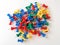 Top view of colorful plastic push pins on white paper background