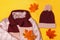 Top view of the composition of warm childrens clothing and autumn leaves on a yellow background