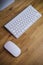 Top view of a computer monitor with a blank screen on a pure white background of a brick wall and a keyboard and mouse on a wooden