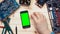 Top view computer technician showing multiple gestures on smart phone with green screen at wooden desk with tools and