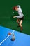 Top view. Concentrated young man in shirt and underwear playing table tennis with whiskey glass over green background.