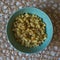 Top view of cooked seasoned rigatoni pasta in a green bowl against a burlap mesh