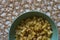 Top view of cooked seasoned rigatoni pasta in a green bowl against a burlap mesh