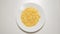 TOP VIEW: Corn flakes appear on a white dish on a white table stop motion