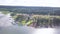 Top view of cottage village by lake. Clip. Country modern cottages with green lawn areas standing on shore of lake on