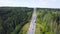 Top view of countryside highway in forest area. Clip. Rural road with traffic of cars and trucks going to city on