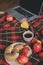 Top view of cozy autumn morning at home. Breakfast with laptop, cup of tea and bagel with apples on woolen plaid blanket