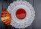 top view of croissant and cup of tea on teabag on paper doily and wooden background