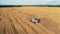 Top view of a crops field getting reaped by a combine