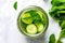 top view of a cucumber slice, mint leaf, and stirred water in a mason jar