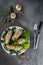 Top view cucumbers stuffed with mushroom and nut salad on a white plate, grey cement background with cutlery, concept of menu for