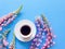 Top view of a cup with black coffee and pink purple peach flowers on a deep blue background. Lupine with long stem.