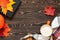 Top view of a cup of coffee, book, plaid scarf, pumpkin and colourful leaves on the wooden table. Slow living concept.