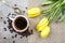 Top view of cup of coffee and bouquet of yellow tulips