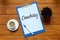 Top view of a cup of coffee,pen,plant and paper written with Coaching on wooden background.