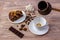 Top view of a cup of coffee and a piece of delicious cake on a saucer, coffee beans, a bowl with sugar cubes, chocolate bar and an