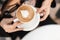 Top view a cup of hot cappuccino with foam in a white vintage cup in female hands. Fashionable young woman in stylish sunglasses