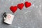 Top view of a cup and red hearts falling out from it on cement background. Happy Valentine`s Day concept