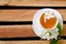 Top view of a cup of tea with flowers and a sprig of jasmine on a wooden table