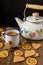 Top view of cup of tea with orange, rustic teapot, on table with gingerbread cookies and cinnamon