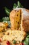 Top view of cut panettone on wooden table with Christmas decoration and green leaves, black background