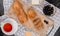 top view of cut and sliced black baguette with cup of tea butter olive on plaid cloth and wooden background