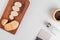 top view of cut and sliced potato on cutting board with salt black pepper and potato chip cutter on white background