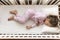Top view Cute little 3-4 years preschool baby girl kid sleeping sweetly in white crib during lunch rest time in pink pajama with