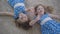 Top view of cute little Caucasian girls waving at camera and smiling. Joyful brunette twin sisters having fun as resting