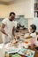 Top view of cute little daughters joining their father cooking pie