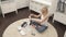 A top view of a cute pregnant blonde sitting on the carpet. She folding baby`s T-shirts