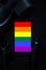 Top view dark tone LGBT grooming concept with image of a LGBTQ+ flag Pride symbol on black table background.