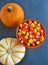 Top view of decorative Halloween pumpkins and bright orange, yellow and white candy corn, a traditional American seasonal sweet.