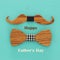 Top view of decorative wooden male bowtie and moustache over blue background.